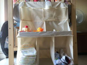 Rangement des affaires bébé dans étagères à suspendre à la table à langer